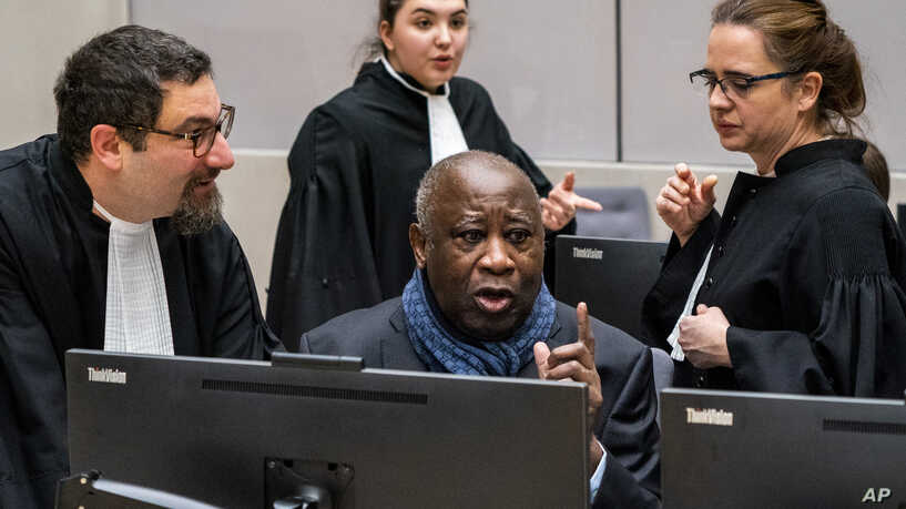 Former Ivory Coast president Laurent Gbagbo talks to his members of his legal team at the International Criminal Court in The Hague, Netherlands, Thursday, Feb. 6, 2020. The ICC hears an appeal by Gbagbo against conditions imposed on him and a former government minister during their release from custody pending prosecutors' appeal against their acquittals on crimes against humanity charges. (Jerry Lampen/Pool photo via AP)