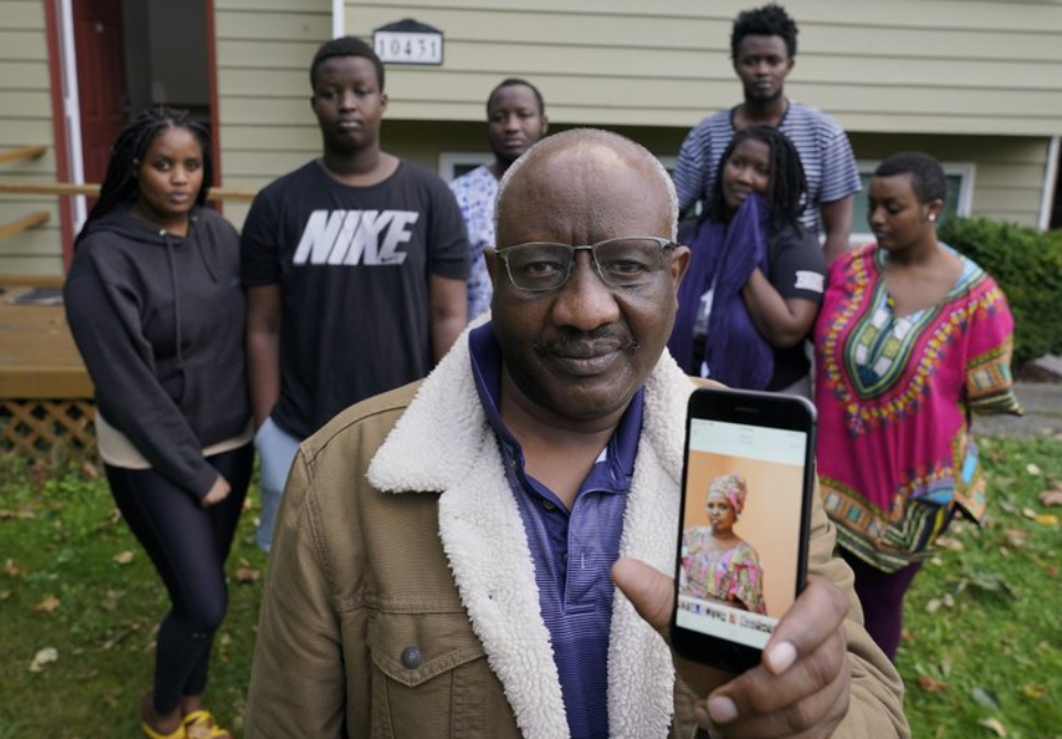 Sophonie Bizimana, center, a permanent U.S. resident who is a refugee from Congo, poses for a photo, Wednesday, Oct. 14, 2020, at his home in Kirkland, Wash., along with six of his children as he displays a cell-phone photo of his wife, Ziporah Nyirahimbya, who is in Uganda and has been unable so far to join him in the U.S. For decades, America admitted more refugees annually than all other countries combined, but that reputation has eroded during Donald Trump's presidency as he cut the number of refugees allowed in by more than 80 percent. - [Photo/AP Photo/Ted S. Warren)
