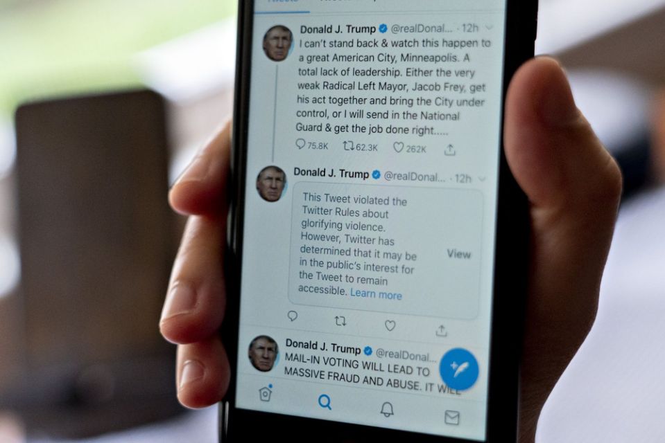 A tweet hidden with a rule-violation notice that includes the phrase "when the looting starts, the shooting starts" by U.S. President Donald Trump is displayed on a smartphone in an arranged photograph taken in Arlington, Virginia, U.S., on Friday, May 29, 2020. Tensions between Twitter Inc. and Trump soared after the social-media platform warned users that the president broke its rules against violent speech, prompting critics to accuse the company of unfairly censoring one of its most prominent users.