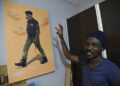 AFP | Artist Julius Agbaje shows a painting of a police officer with dog's head, entitled 'Mad Dog'