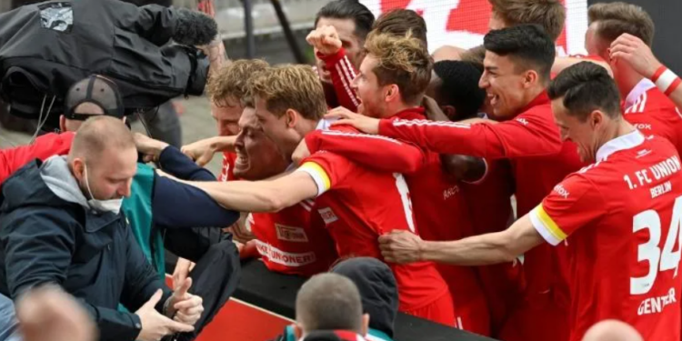 Union Berlin striker Max Kruse (C) is mobbed by team-mates after his winning goal | AFP