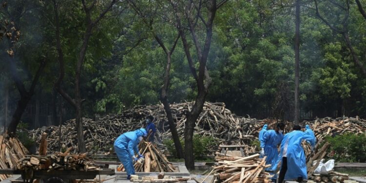 Health workers prepare the funeral pyres of people who have died of Covid-19 at a cremation ground in New Delhi, India | AFP