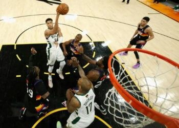 Milwaukee star forward Giannis Antetokounmpo makes a leaping pass over Phoenix guard Chris Paul in game one of the NBA Finals | AFP