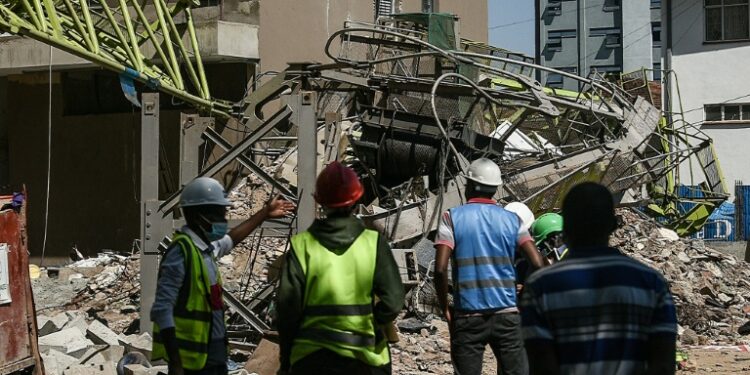 Contractors stand next to the collapsed crane in Kenya's capital Nairobi, on August 26, 2021 | AFP