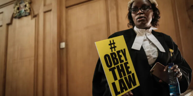 Law Society of Kenya official Mercy Wambua holds a placard at the Supreme Court in Nairobi after a protest over government disobedience of court orders |  Yasuyoshi Chiba/AFP via Getty