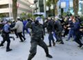 Tunisian demonstrators run for cover during clashes with police during a protest against President Kais Saied, on the 11th anniversary of the Tunisian revolution in the capital Tunis on January 14, 2022 | AFP