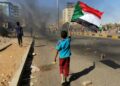 A young boy waves a Sudanese national flag as protesters block a street in the capital Khartoum, during a demonstration against the killing of dozens in a crackdown since last year's military coup, on January 20, 2022 | AFP