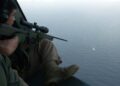 This undated handout photo released by South Korea's military on May 4, 2009 shows South Korean soldiers aboard a helicopter aiming a sniper rifle at a pirate boat after repelling its attack on a North Korean ship in waters off Somalia | AFP