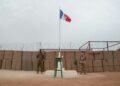 A Malian and a French soldier stand either side of a flagpole at a French base in Timbuktu before a ceremony last December to hand the facility over to the Malian military. Since then, France has announced a full pullout from Mali | AFP