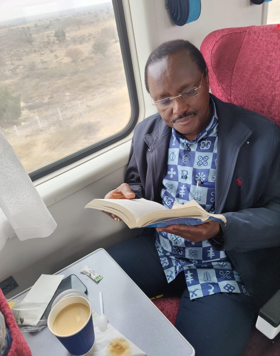 Kalonzo Musyoka reading a book during his trip via the SGR. PHOTO/Kalonzo.